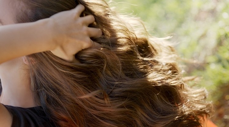 Frau fässt sich ins volle Haar